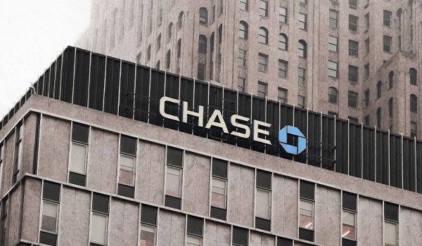 Chase Bank logo on the bank's building with a skyscraper in the background.